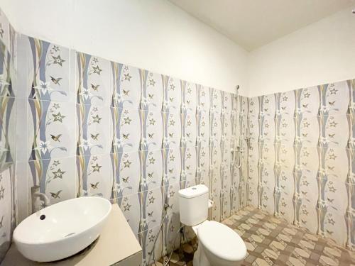 a bathroom with a toilet and a sink at Urbanview Hotel Lilis Ikvala Radha in Canggu