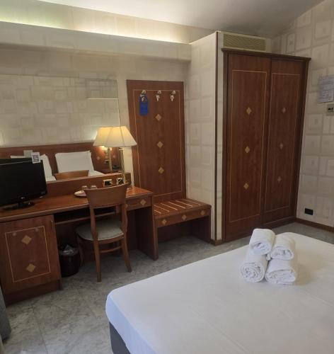 a hotel room with a desk and a bed with towels at Hotel Chelsea in Turin
