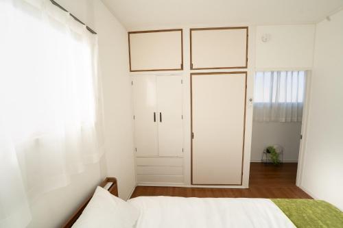 a bedroom with white walls and a white closet at Encounter Dazaifu in Dazaifu