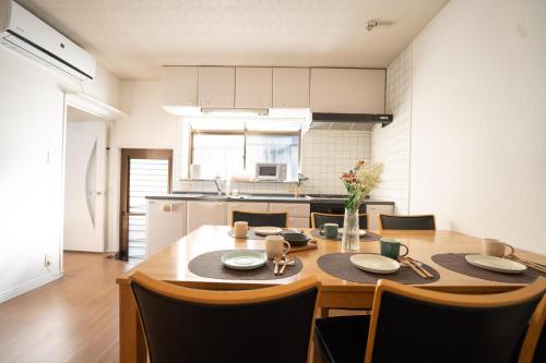 a kitchen with a wooden table with chairs and a dining room at Encounter Dazaifu in Dazaifu