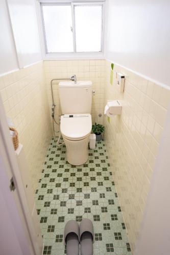 a bathroom with a toilet with a tile floor at Encounter Dazaifu in Dazaifu