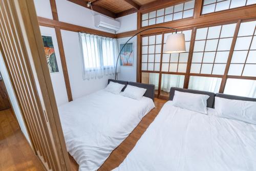 two beds in a room with windows at Encounter Dazaifu in Dazaifu