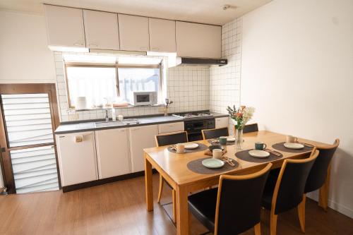 a kitchen with a wooden table and chairs and a kitchen with white cabinets at Encounter Dazaifu in Dazaifu