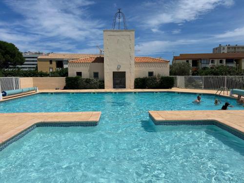 une grande piscine avec des gens dans l'eau dans l'établissement Villa T2 à 100m de la plage, piscine, tennis, à Saint Cyprien Plage