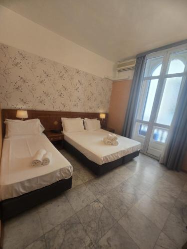 two beds in a hotel room with a window at Hotel Chelsea in Turin