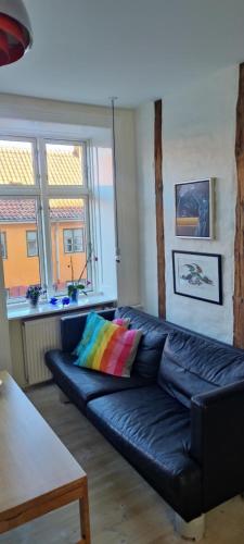 a black leather couch in a living room with a table at I hjertet af København nær Marmorkirken Metro in Copenhagen