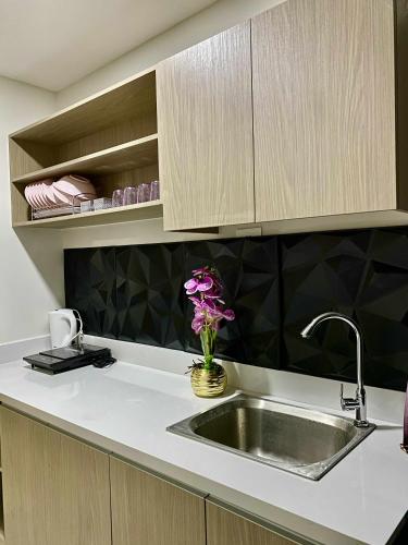 a kitchen counter with a sink and a vase of flowers at Near Airport Casa Isabel Primeworld in Agus