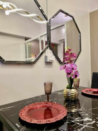 a table with two plates and a vase with purple flowers at Near Airport Casa Isabel Primeworld in Agus