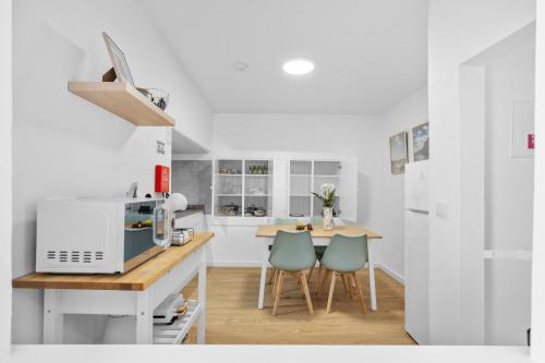 a white kitchen with a table and two chairs at Luzia by the Sea - T1 Acolhedor a Passos da Praia in Calheta