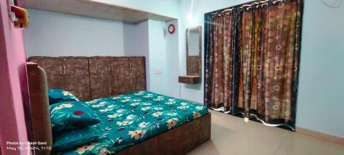 a bedroom with a bed with a green comforter at Marigold Bungalow in Kelavli
