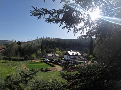 a house on a hill with a green field and trees at Pension V údolí v Jizerských horách in Josefuv dul