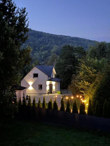 a white house with lights in a yard at night at Dablin 9 in Korbielów
