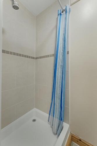 a bath tub with a blue shower curtain in a bathroom at Bank View Barn at Pound Farm in Crook