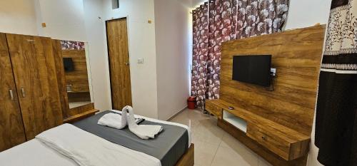 a bedroom with a bed and a tv on a wall at Hotel Aaryodaya in Ahmedabad