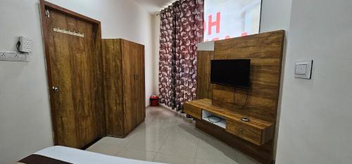 a room with a television and a wooden wall at Hotel Aaryodaya in Ahmedabad