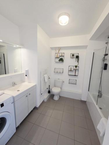 a white bathroom with a toilet and a sink at Charmant T2 avec grande terrasse in Saint-Nazaire