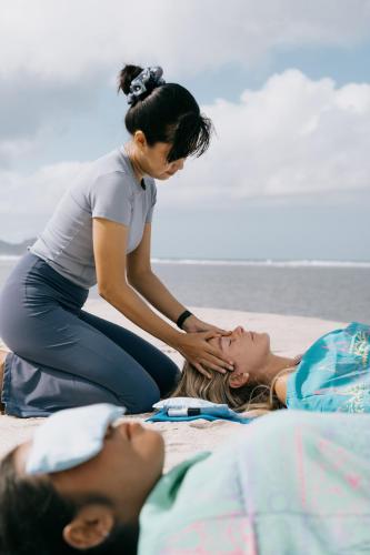 a woman is sitting on the beach with a woman at Amber Lombok Beach Resort in Selong Belanak