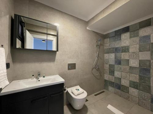 Un baño con lavabo, inodoro y espejo. en Lina Life, en Fethiye