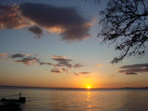 a sunset over a body of water with a boat at Caballito's Mar in Ometepe