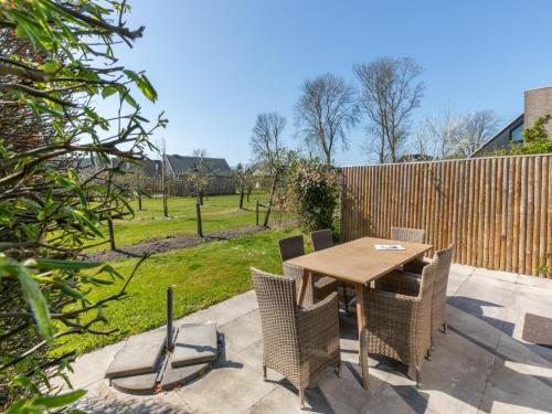 a wooden table and chairs on a patio at Holiday Home near Beach with Pool Access in Burgh Haamstede
