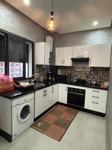 cocina con armarios blancos y lavadora en Appartement 50 m Ocean, en Kenitra