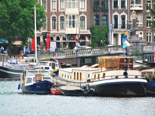 two boats are docked in the water near buildings at art deco houseboat on super location in Amsterdam
