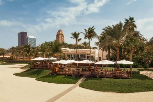 a resort with tables and umbrellas and palm trees at One&Only Royal Mirage Resort Dubai in Dubai