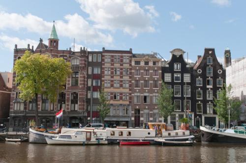 a group of boats docked in the water in front of buildings at art deco houseboat on super location in Amsterdam