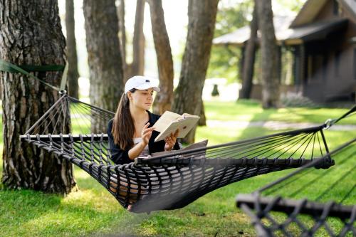 a woman sitting in a hammock reading a book at Мис Доброї Надії Полтава in Hlody