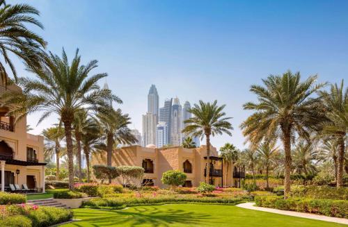 a garden with palm trees and a city in the background at One&Only Royal Mirage Resort Dubai in Dubai