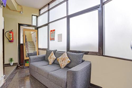 a living room with a couch and large windows at Hotel O Parppidam Residency Kazhakuttam Railway Station in Kazhakuttam