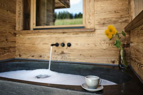a cup of coffee in a tub in a wooden bathroom at Ziegelberg Chalets in Füssen