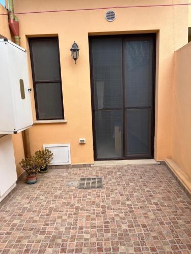 a house with black doors and a brick patio at Via Roma House Casetta in Terralba