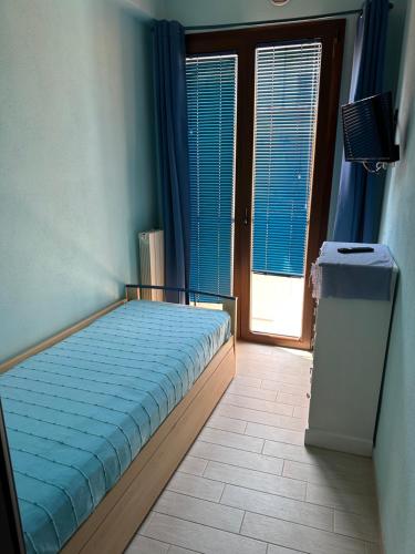a bedroom with a bed and a window with blue curtains at Via Roma House Casetta in Terralba