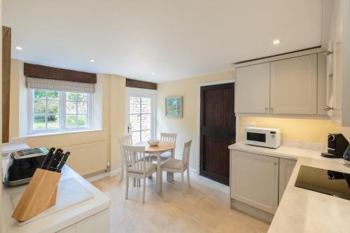 a kitchen with white cabinets and a table and chairs at The Gate House in Peterborough