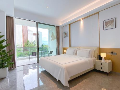 a bedroom with a white bed and a large window at Begonia Hotel in Sanya