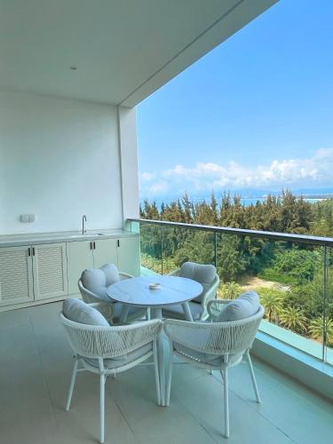 a room with a table and chairs on a balcony at Begonia Hotel in Sanya