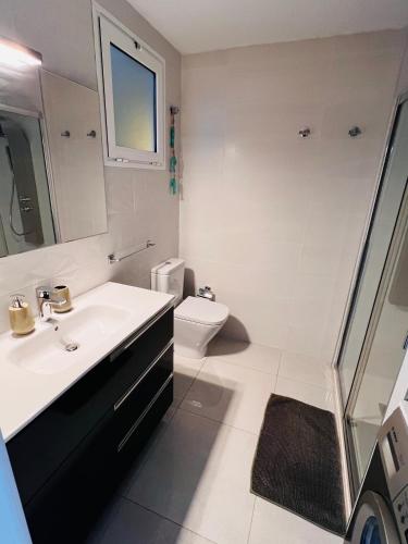 a white bathroom with a sink and a toilet at Las Mareas Sea View Terrace 3 min to Beach in Morro del Jable