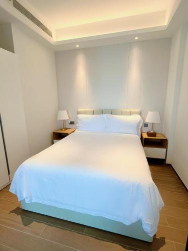 a large white bed in a room with two lamps at Begonia Hotel in Sanya