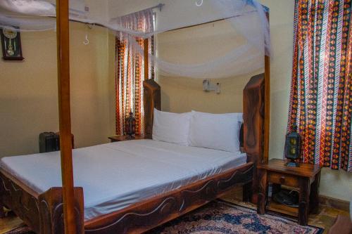 a bedroom with a canopy bed with white sheets at Lannan Escapes in Diani Beach