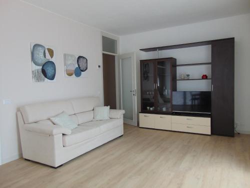 a living room with a white couch and a television at Torre 2 in Longarone