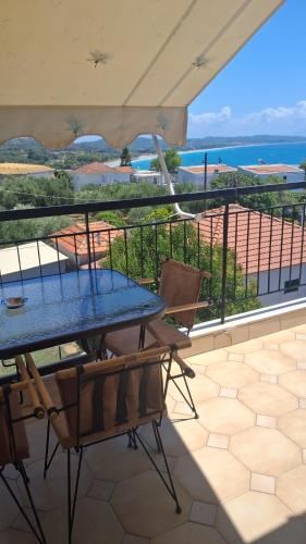 a table and chairs on a balcony with a view of the ocean at Royal Apartments in Pídima Kyrás
