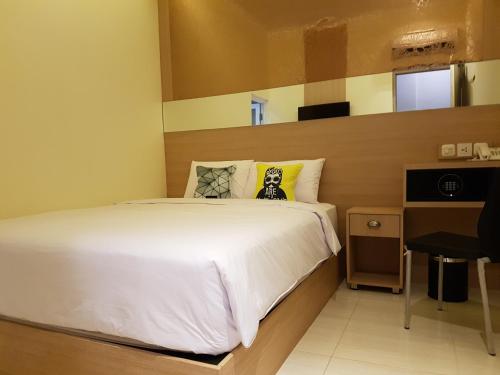 a bedroom with a white bed and a desk at Bold Hotel Jakarta in Jakarta