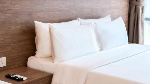 a white bed with white pillows in a room at Cottonhouz by Ayuhouz in Kota Kinabalu