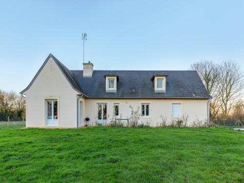 a white house with a black roof on a grass field at Tranquil Garden Retreat by the Sea in Englesqueville-la-Percée