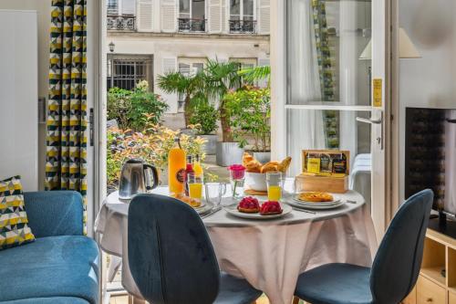 a table with breakfast food on it in a room with a window at La Maison Kléber - Luxury apartments, Champs-Elysées - Eiffel Tower in Paris