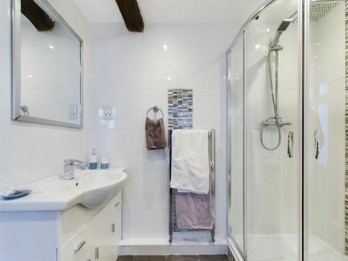 a white bathroom with a sink and a shower at Woodman's Cottage, Penrith in Penrith