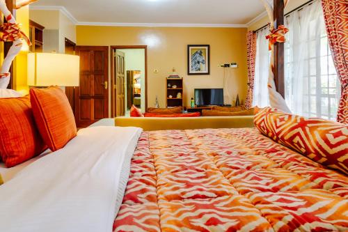 a large bed with an orange and white blanket at selvasara suites in Nairobi