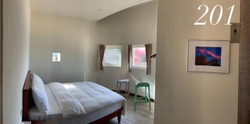 a bedroom with a bed and a green chair at Horn Seaside Homestay in Nangan