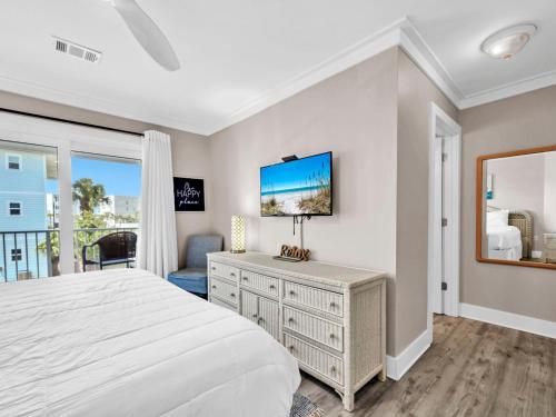 a bedroom with a bed and a tv on a wall at Beachside Villas 122- Sun for the Roses in Santa Rosa Beach